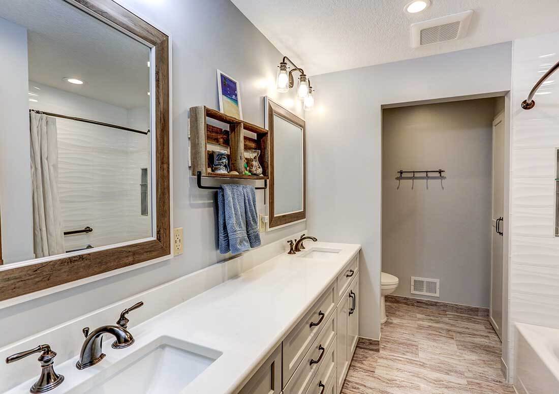 Twin Cities bathroom renovation project featuring double sinks with upgraded tile floors, white countertops, and new hardware from Titus Contracting.