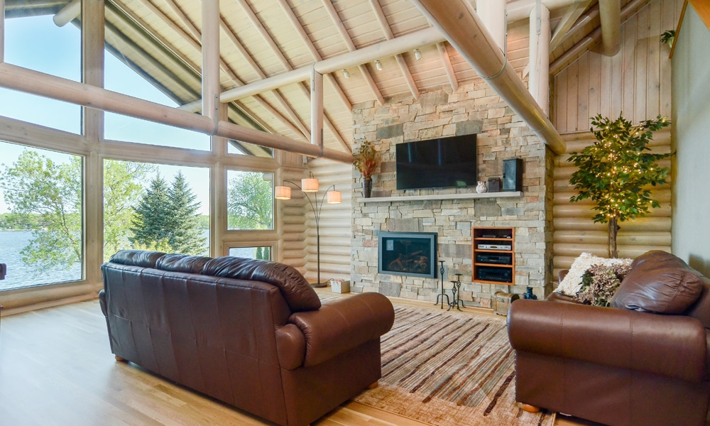 Living room renovation project from Titus Contracting features rustic wooden beams and stone surround fire place.