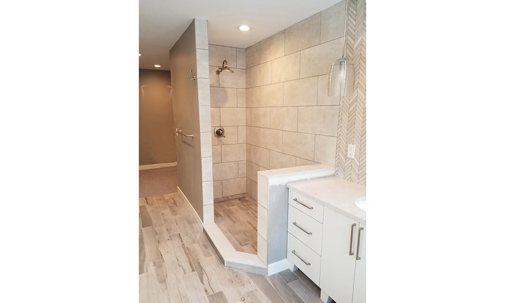 Residential bathroom renovation including large, tiled walk-in shower and wood-style tile flooring completed by Titus Contracting.