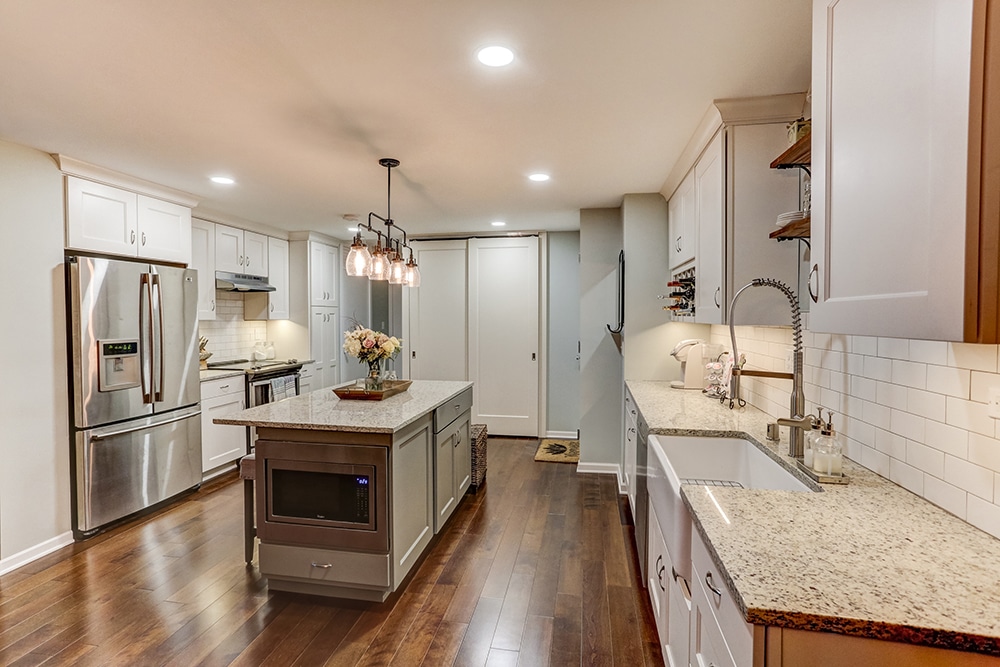Residential kitchen remodel by Titus Contracting in the Twin Cities, MN includes fresh and modern white cabinets, granite countertops and wood flooring with stainless steel appliances in an open floorplan.