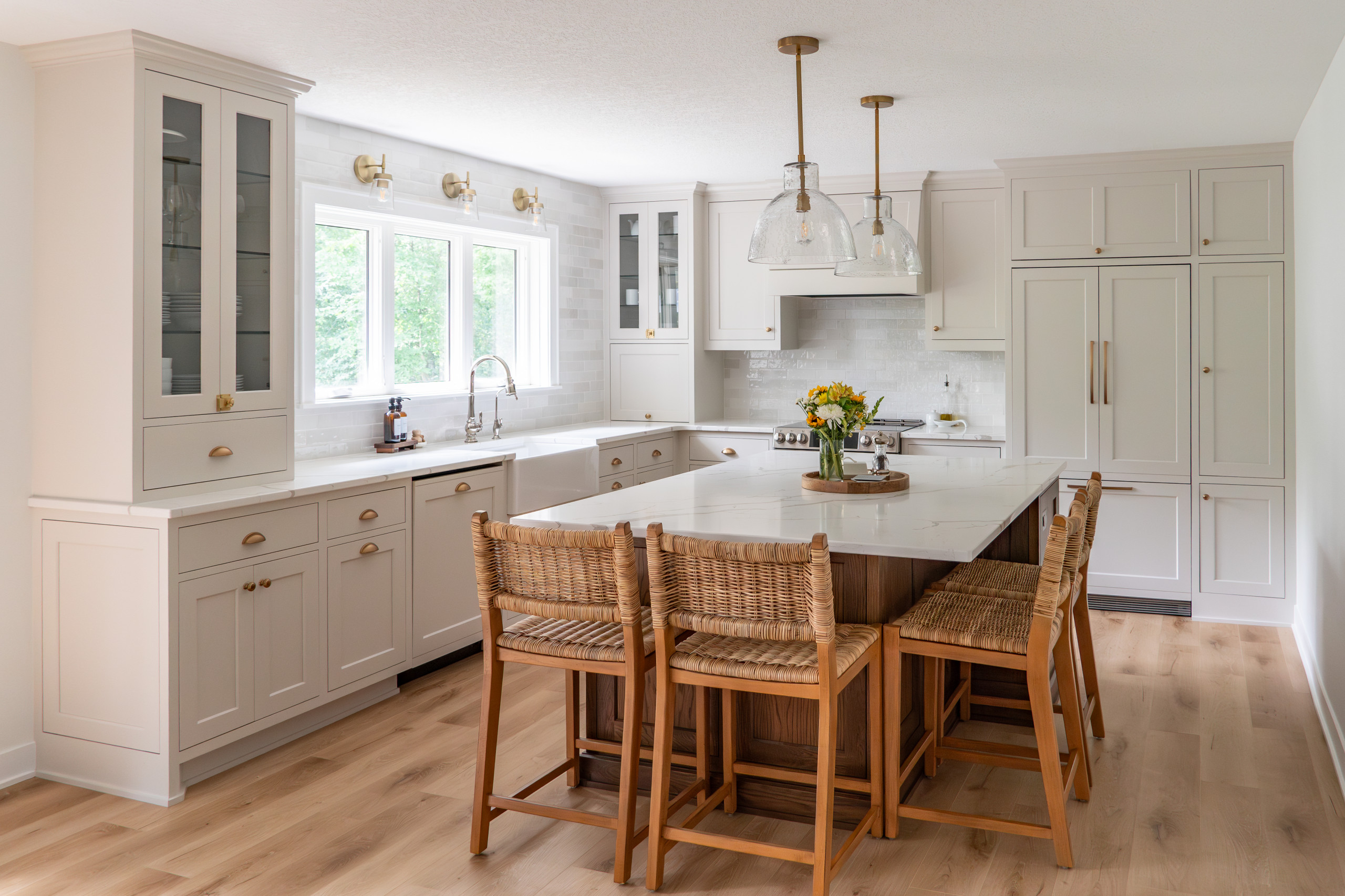 a kitchen with white cabinets and countertops and warm wooden furniture accents