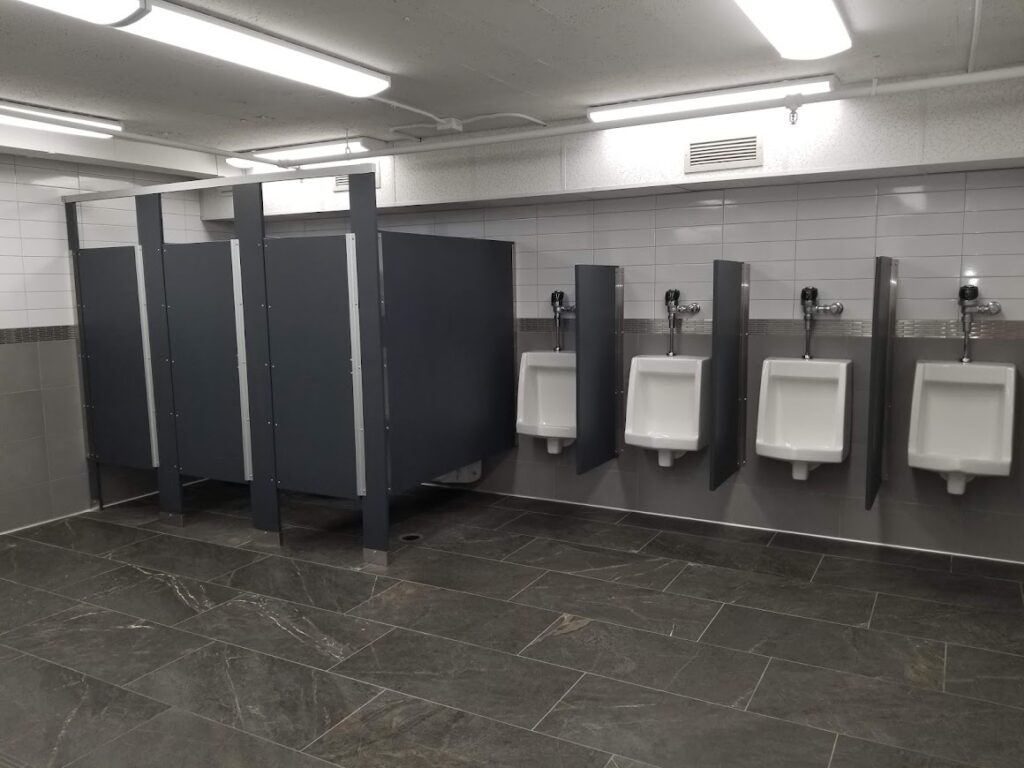 a row of stalls and urinals in a commercial bathroom